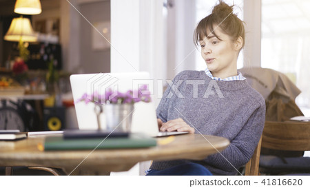 A young surprised cute brunette girl is working with a laptop in a cafe 41816620