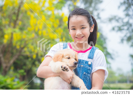 girl holding a little golden retriever dog in park girl holding a little golden retriever dog in park 41823578