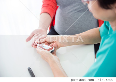 Nurse checking pregnant woman's blood sugar Nurse checking pregnant woman's blood sugar 41823800