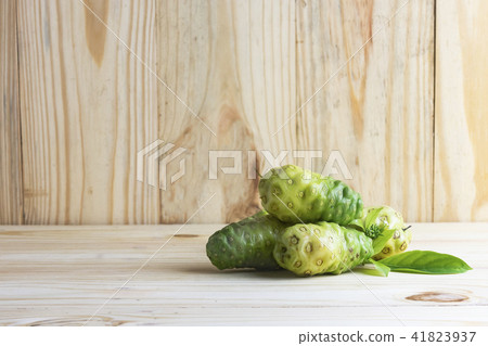 Noni fruit and leaves on wooden table and wooden b Noni fruit and leaves on wooden table and wooden b 41823937