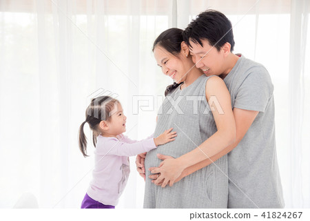 girl touching her pregnant mother belly and smiles 41824267