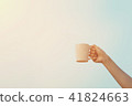 Human hand holding white coffee cup up to the air  41824663