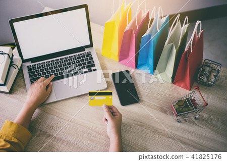 Young woman typing laptop for online shopping website and holdin Young woman typing laptop for online shopping website and holdin 41825176