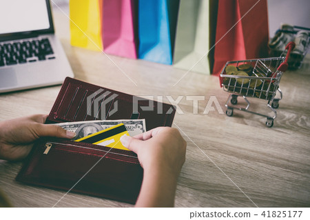 Image of Young woman giving credit card from wallet for online s Image of Young woman giving credit card from wallet for online s 41825177