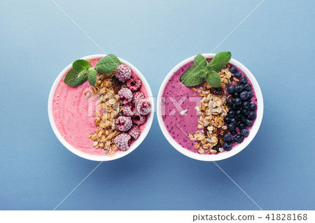 Two smoothie bowls with granola and berries. 41828168