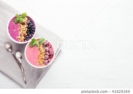 Two smoothie bowls with granola and berries. 41828169