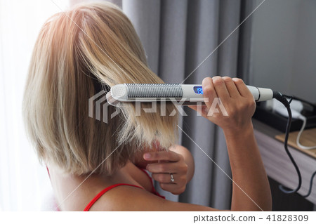 Hairdresser straightening long brown hair. 41828309