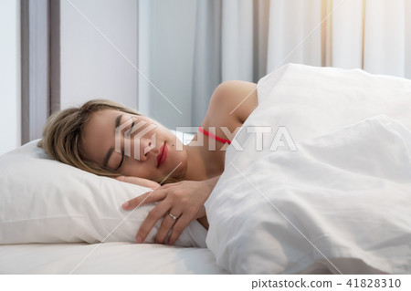 Young smiling pretty lady lies in bed indoors Young smiling pretty lady lies in bed indoors 41828310