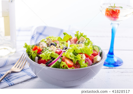 Fresh greek salad served in bowl with glass wine. Fresh greek salad served in bowl with glass wine. 41828517