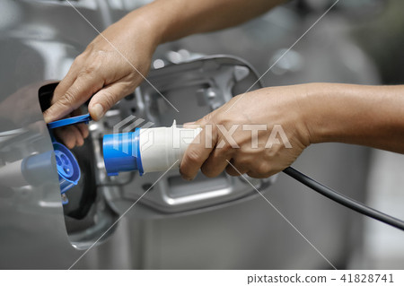 Charging electric car with power supply plugged in Charging electric car with power supply plugged in 41828741