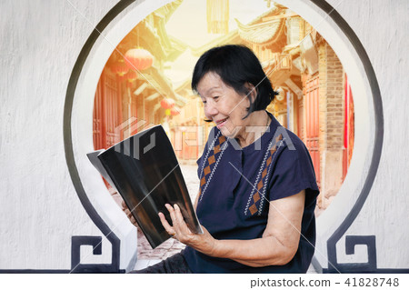 elderly woman reading magazine in chinese oldtown 41828748