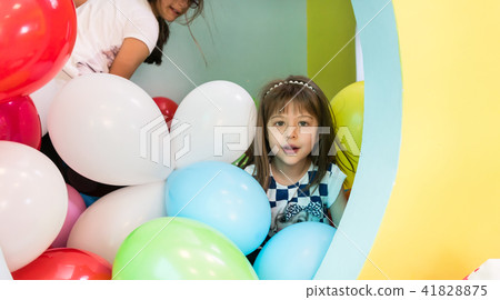 Two cute girls talking while playing with multicolored balloons Two cute girls talking while playing with multicolored balloons 41828875