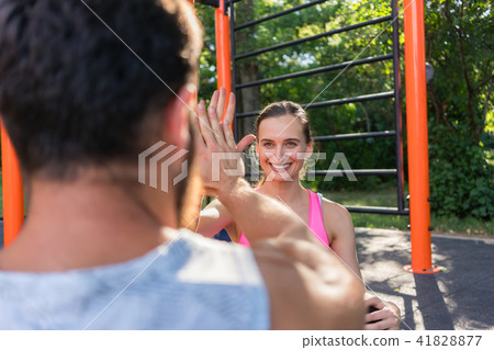 Cheerful young woman giving high-five to her partner while doing crucnches Cheerful young woman giving high-five to her partner while doing crucnches 41828877
