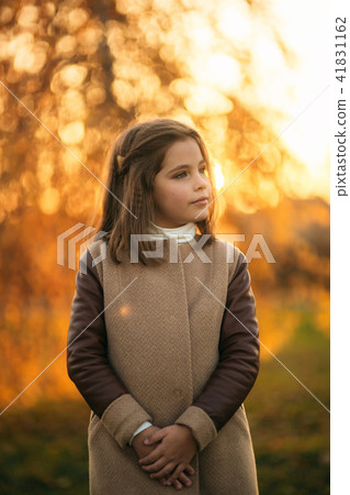 Little girl in autumn coat posing for photographer. Golden autumn Little girl in autumn coat posing for photographer. Golden autumn 41831162