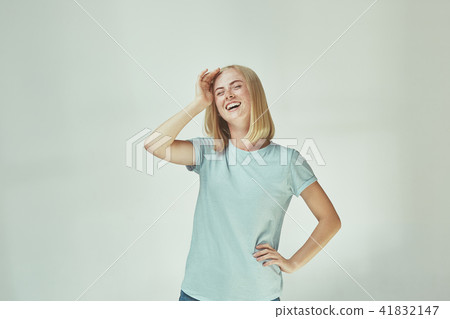 The happy freckled woman standing and smiling against gray background. The happy freckled woman standing and smiling against gray background. 41832147