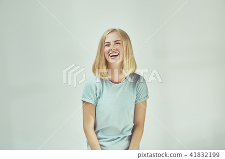 The happy freckled woman standing and smiling against gray background. 41832199