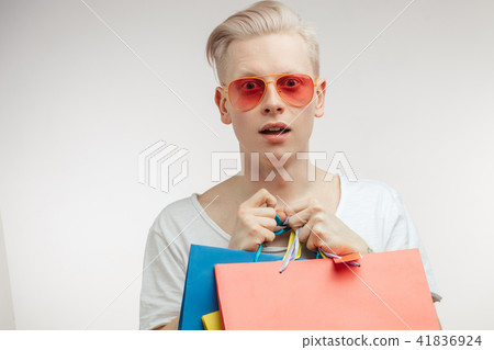 Portrait of fashion young man in pink glasses with shopping bags 41836924