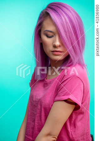 Attractive girl with pink hair, dressed in casual pink cloth on blue background. 41836980