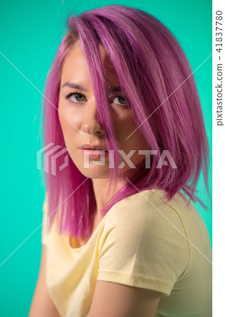 attractive young woman with wearing violet loose hair isolated at blue wall 41837780