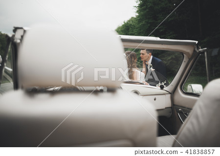 Stylish wedding couple, bride, groom kissing and hugging on retro car Stylish wedding couple, bride, groom kissing and hugging on retro car 41838857