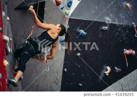 Woman reaching the top of artificial bouldering wall while exercising in gym. 41839205