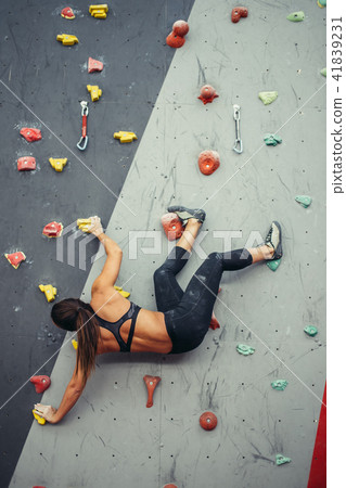 Beautiful young woman taking a big step up an artificial wall Beautiful young woman taking a big step up an artificial wall 41839231