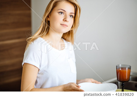 Attractive blonde woman posing at table in her kitchen Attractive blonde woman posing at table in her kitchen 41839820