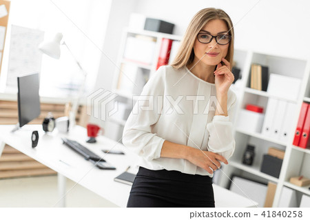 A young girl is standing leaning on a table in the office. A young girl is standing leaning on a table in the office. 41840258