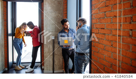 Confident young businessman using smartphone standing at the window in office 41840584