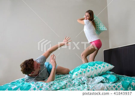 Young couple having fun in bedroom with pillow fight 41843937
