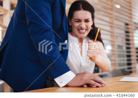 Indignant woman hitting mans hand with a pencil Indignant woman hitting mans hand with a pencil 41844160