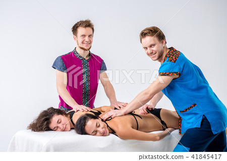 Theme massage and body care. Two young male twin brothers with a beard and uniform make a tandem Theme massage and body care. Two young male twin brothers with a beard and uniform make a tandem 41845417
