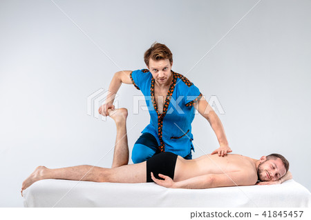 Theme massage and body care. A handsome Caucasian man in blue uniform and beard does stretching 41845457