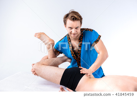 Theme massage and body care. A handsome Caucasian man in blue uniform and beard does stretching 41845459