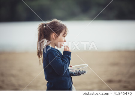 The girl eating blueberries from a glass bowl The girl eating blueberries from a glass bowl 41845470