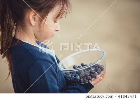 The girl eating blueberries from a glass bowl The girl eating blueberries from a glass bowl 41845471