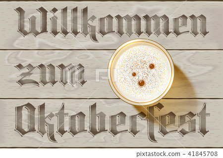 Glass of Beer on wooden background with german inscription Willkommen zum Oktoberfest. Top view on Beer Mug with foamy lager with bubbles. Realistic shadow, foam, table. Vector Illustration. No Mesh 41845708