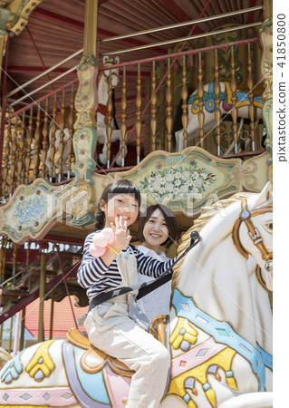 Father and girl riding a merry-go-round amusement park 41850800