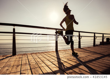 runner running on seaside boardwalk during sunrise 41853145