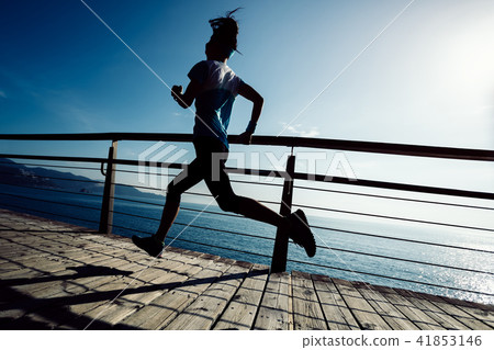runner running on seaside boardwalk during sunrise runner running on seaside boardwalk during sunrise 41853146