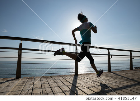 runner running on seaside boardwalk during sunrise 41853147