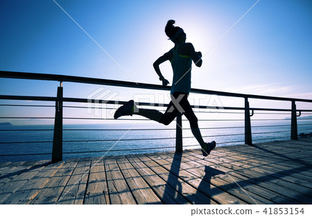 runner running on seaside boardwalk during sunrise runner running on seaside boardwalk during sunrise 41853154