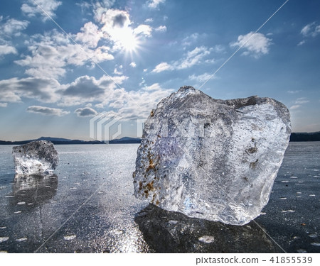 Ice shards on a frozen lake. The rays of the sun  41855539