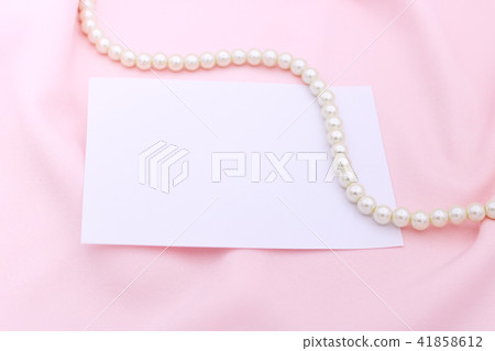Pearl necklace on the pink fabric with paper note. 41858612