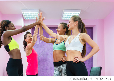 Happy fit women putting hands together before group workout class 41859605