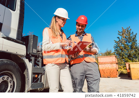 Worker signing papers to have delivered demolition rubble container Worker signing papers to have delivered demolition rubble container 41859742