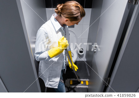 Cleaning lady or janitor mopping the floor in restroom 41859826