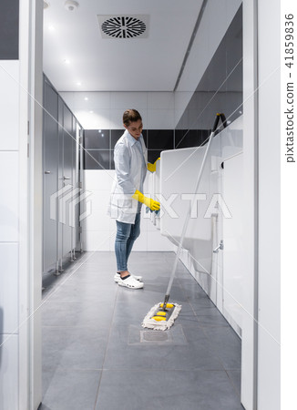 Janitor woman cleaning urinals in public toilet  41859836