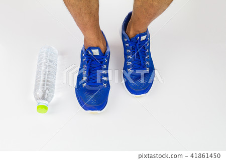 Legs, sport shoes and water bottle on white floor 41861450
