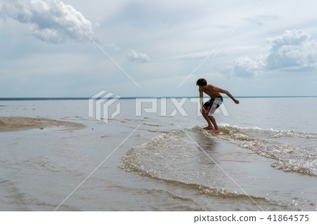 a young man goes in for skimboarding on the water 41864575